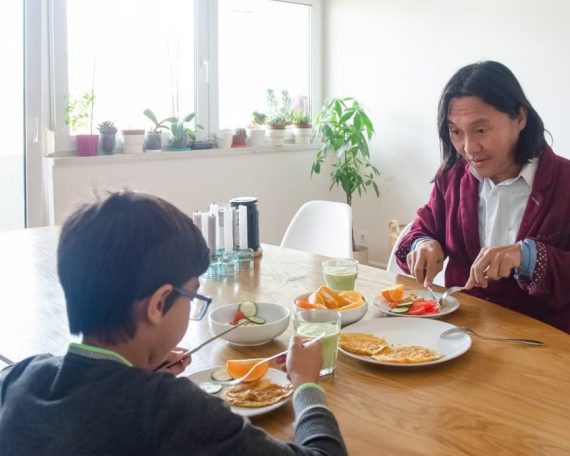 Father and son enjoying a healthy breakfast together at home in Portugal.